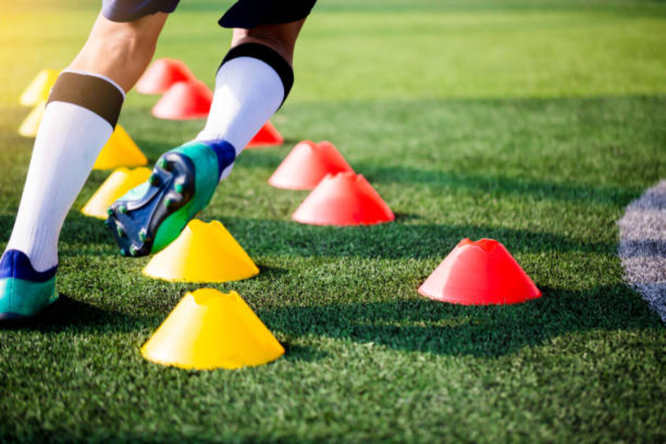 Soccer player Jogging and jump between cone markers on green artificial turf for soccer training. Football or Soccer Academy.